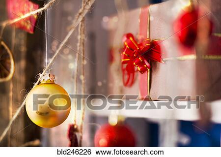 Ornaments hanging on string near gift box View Large Photo Image Stock Photograph - Ornaments hanging on string near gift box. Fotosearch