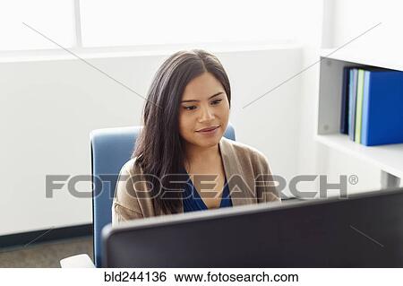 Stock Photograph - Pacific Islander woman using computer in office. Fotosearch