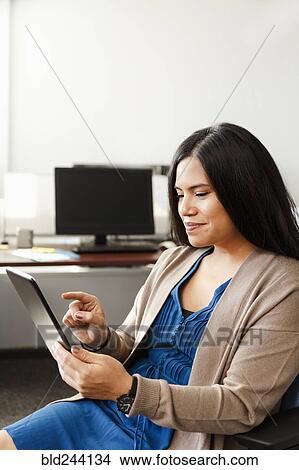 Pacific Islander woman using digital tablet in office View Large Photo Image Picture - Pacific Islander woman using digital tablet in office. Fotosearch