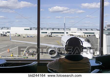 Passenger listening to headphones at airport View Large Photo Image Picture - Passenger listening to headphones at airport. Fotosearch