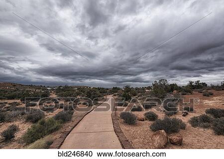 Stock Image - "Path under clouds in Arches National Park, Moab, Utah, United States". Fotosearch
