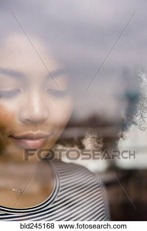 Stock Photo - Pensive African American woman behind window. Fotosearch