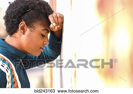 Stock Image - Pensive African American woman leaning on wall. Fotosearch