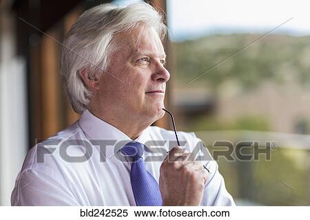 Stock Photography - Pensive Caucasian businessman holding eyeglasses. Fotosearch