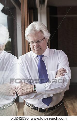 Stock Image - Pensive Caucasian businessman leaning on window. Fotosearch