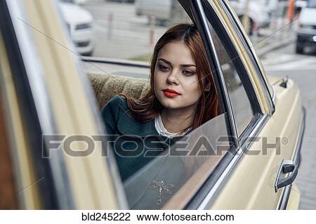 Stock Image - Pensive Caucasian woman in back seat of car. Fotosearch
