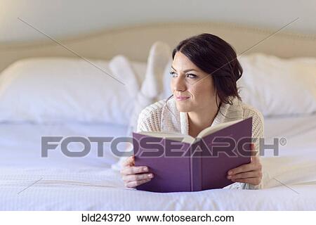 Pensive Caucasian woman laying on bed reading book View Large Photo Image Stock Image - Pensive Caucasian woman laying on bed reading book. Fotosearch