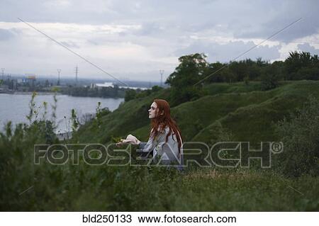 Pensive Caucasian woman sitting on hill near ocean View Large Photo Image Stock Image - Pensive Caucasian woman sitting on hill near ocean. Fotosearch