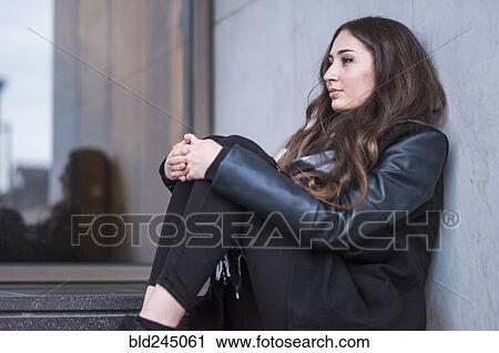 Stock Image - Pensive Caucasian woman sitting on staircase. Fotosearch