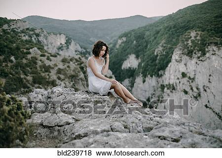 Stock Photo - Pensive Caucasian woman sitting on mountain. Fotosearch