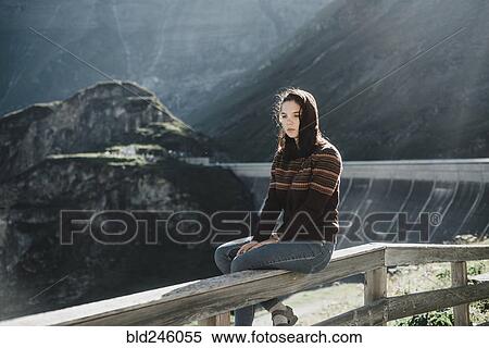 Pensive Caucasian woman sitting on wooden fence View Large Photo Image Stock Photography - Pensive Caucasian woman sitting on wooden fence. Fotosearch