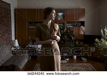 Pensive Caucasian woman standing in livingroom View Large Photo Image Stock Photography - Pensive Caucasian woman standing in livingroom. Fotosearch