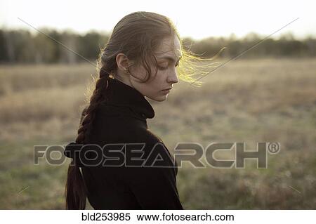 Stock Photography - Pensive Caucasian woman standing in field. Fotosearch
