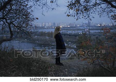 Pensive Caucasian woman standing near urban waterfront at night View Large Photo Image Stock Image - Pensive Caucasian woman standing near urban waterfront at night. Fotosearch