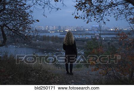 Pensive Caucasian woman standing near urban waterfront at night View Large Photo Image Stock Image - Pensive Caucasian woman standing near urban waterfront at night. Fotosearch
