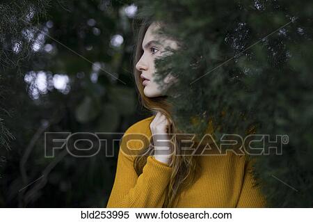 Stock Photography - Pensive Caucasian woman standing near tree branch. Fotosearch