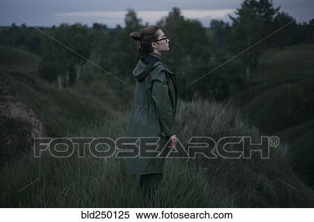Stock Photography - Pensive Caucasian woman standing on hill. Fotosearch
