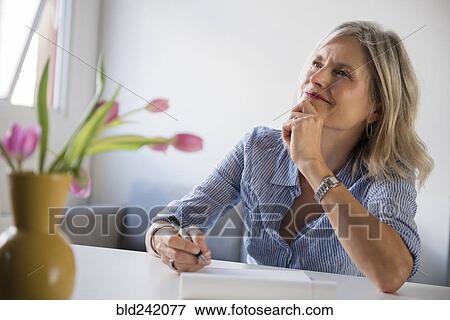 Pensive Caucasian woman writing on notepad View Large Photo Image Stock Photo - Pensive Caucasian woman writing on notepad. Fotosearch