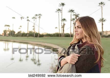 Stock Image - Pensive Hispanic woman near lake. Fotosearch