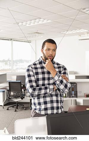Stock Image - Pensive Mixed Race man standing in office. Fotosearch