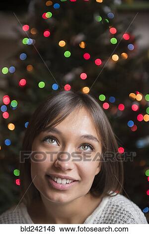 Pensive Mixed Race woman near Christmas tree View Large Photo Image Stock Photo - Pensive Mixed Race woman near Christmas tree. Fotosearch