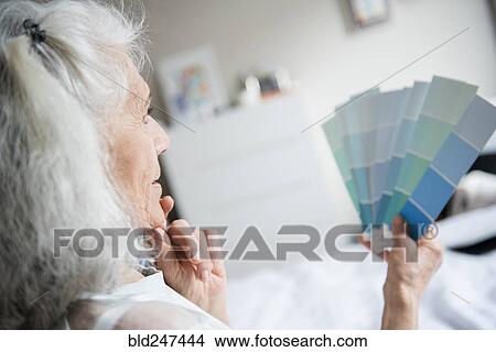 Picture - Pensive older woman examining color swatches. Fotosearch