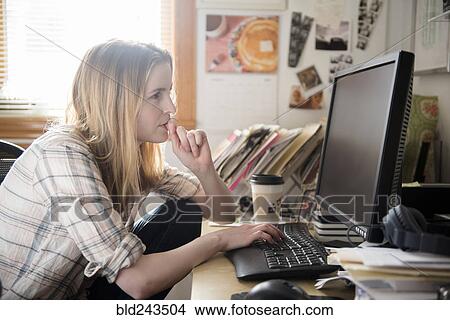 Picture - Pensive woman using computer at desk. Fotosearch
