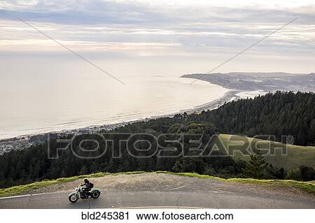 Person riding motorcycle at edge of cliff near ocean View Large Photo Image Stock Image - Person riding motorcycle at edge of cliff near ocean. Fotosearch
