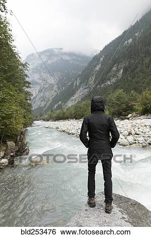 Stock Photograph - Person standing on rock near river. Fotosearch