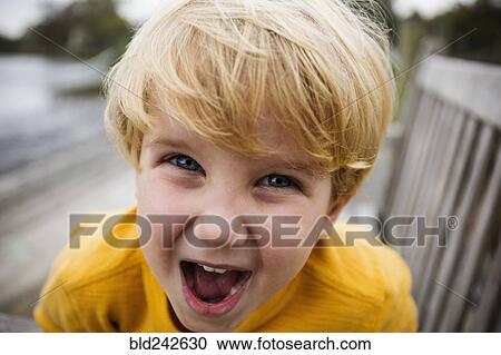Stock Image - Playful Caucasian boy yelling on bench. Fotosearch