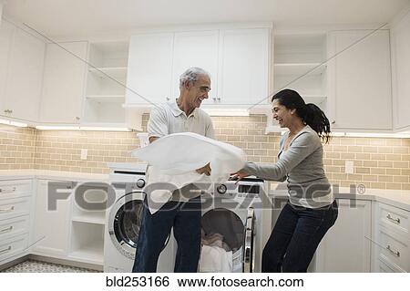 Playful couple folding towel in modern laundry room View Large Photo Image Stock Photograph - Playful couple folding towel in modern laundry room. Fotosearch