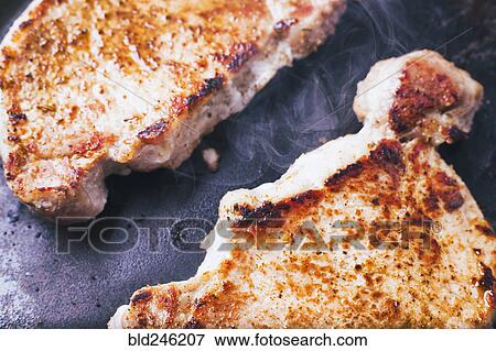 Stock Photo - Pork chops searing in pan. Fotosearch