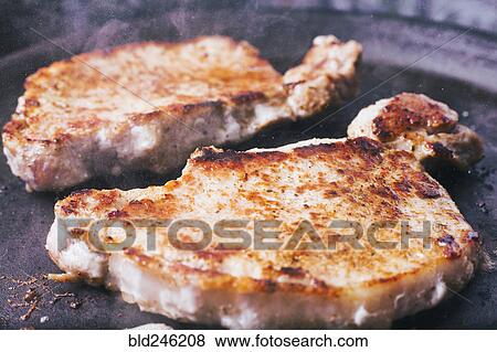 Stock Photo - Pork chops searing in pan. Fotosearch