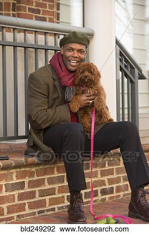 Portrait of African American man sitting on stoop holding dog View Large Photo Image Stock Image - Portrait of African American man sitting on stoop holding dog. Fotosearch