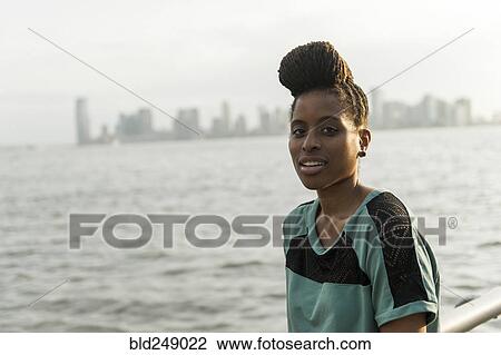Stock Image - Portrait of African American woman with braids at waterfront. Fotosearch