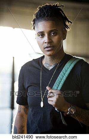 Stock Image - Portrait of androgynous Mixed Race woman carrying backpack. Fotosearch