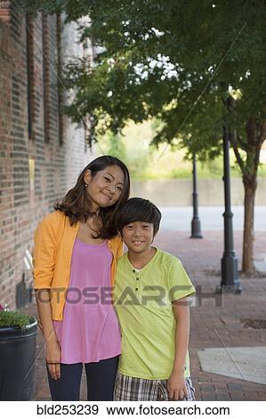 Stock Photo - Portrait of Asian mother and son standing on sidewalk. Fotosearch