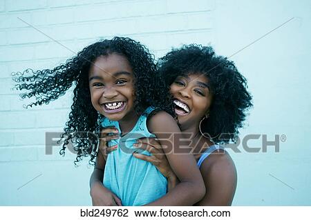 Stock Image - Portrait of Black mother and daughter laughing. Fotosearch