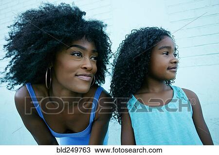 Stock Image - Portrait of Black mother and daughter looking away. Fotosearch