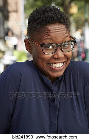 Stock Image - Portrait of Black woman shrugging on city sidewalk. Fotosearch