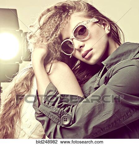 Stock Image - Portrait of Caucasian girl wearing sunglasses near spotlight. Fotosearch