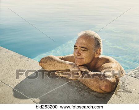 Stock Image - Portrait of Caucasian man relaxing in swimming pool. Fotosearch