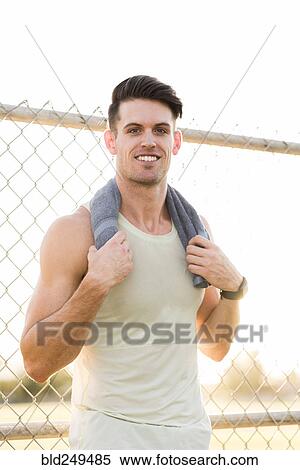 Stock Photography - Portrait of Caucasian man resting with towel outdoors. Fotosearch
