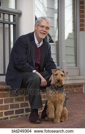 Picture - Portrait of Caucasian man sitting on stoop posing with dog. Fotosearch