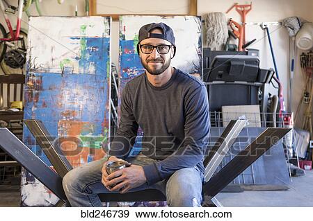 Stock Photo - Portrait of Caucasian man sitting on metal sculpture. Fotosearch