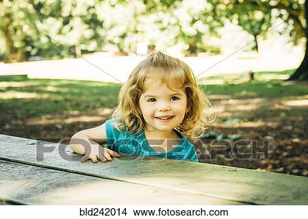 Picture - Portrait of Caucasian preschool girl at picnic table. Fotosearch