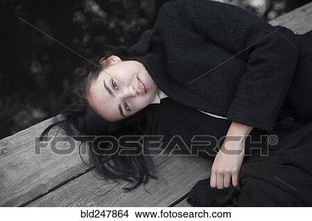 Picture - Portrait of Caucasian woman laying on wood. Fotosearch