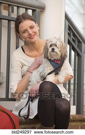 Stock Photo - Portrait of Caucasian woman sitting on stoop holding dog. Fotosearch