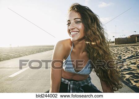 Stock Image - Portrait of Caucasian woman smiling on path at beach. Fotosearch