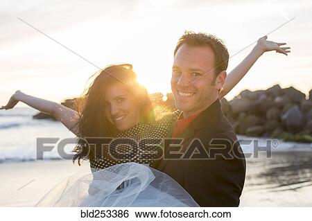 Stock Photograph - Portrait of couple celebrating on beach. Fotosearch
